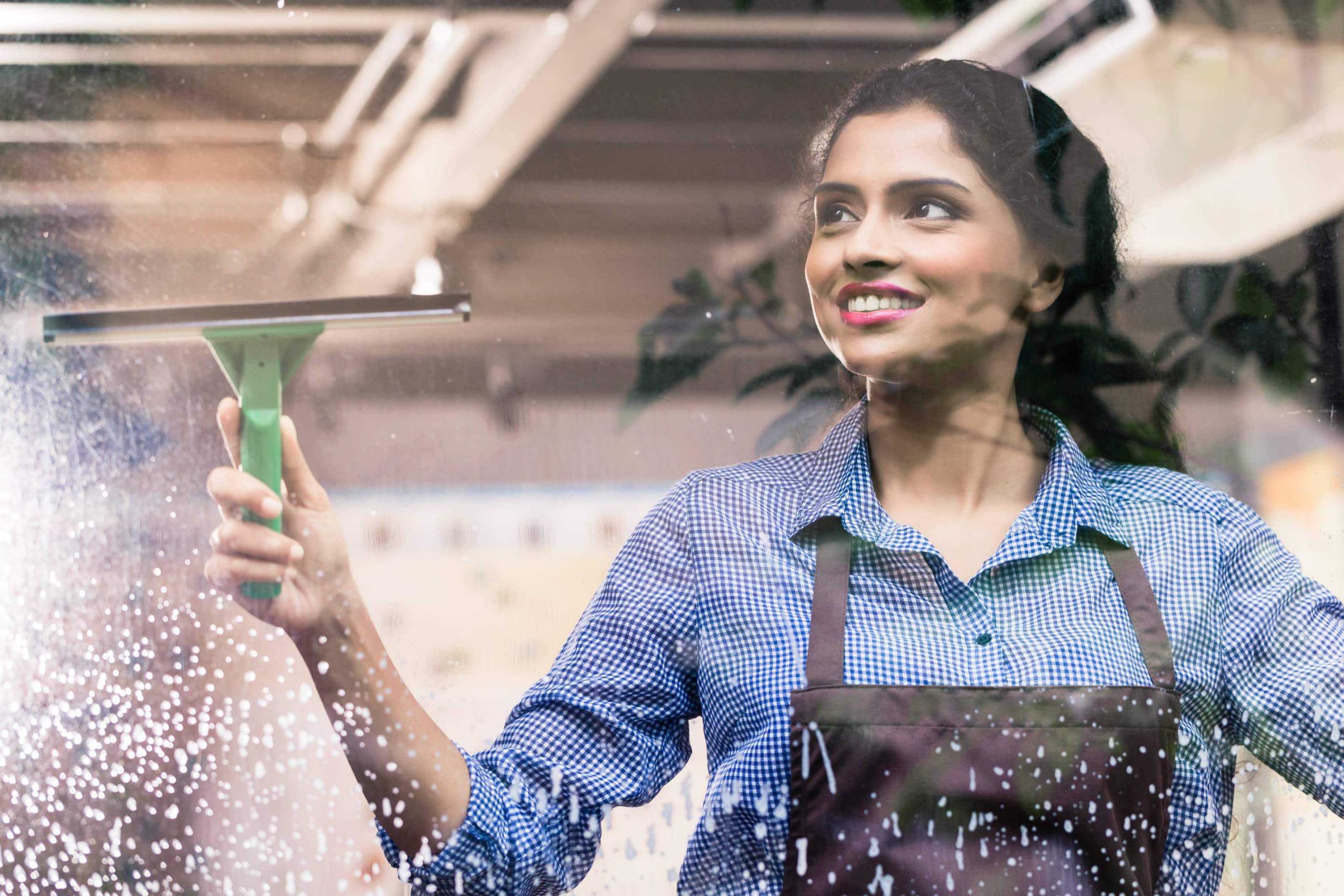 employee cleaning windows with a squeegee