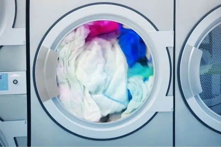 overloaded front loader washing machine with assorted coloured towels inside