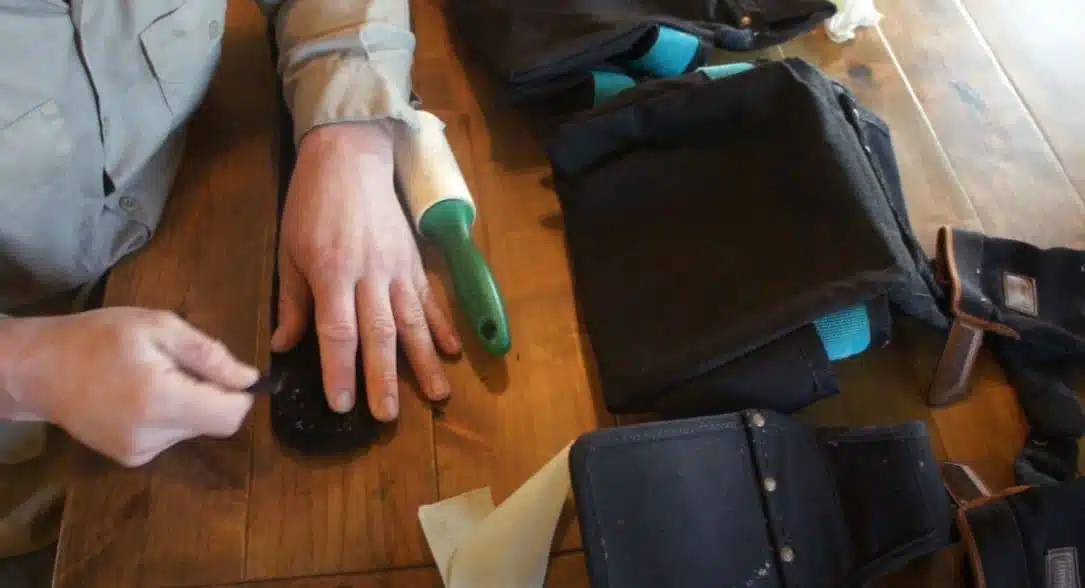 man using a pick to deep clean a velcro bag strap