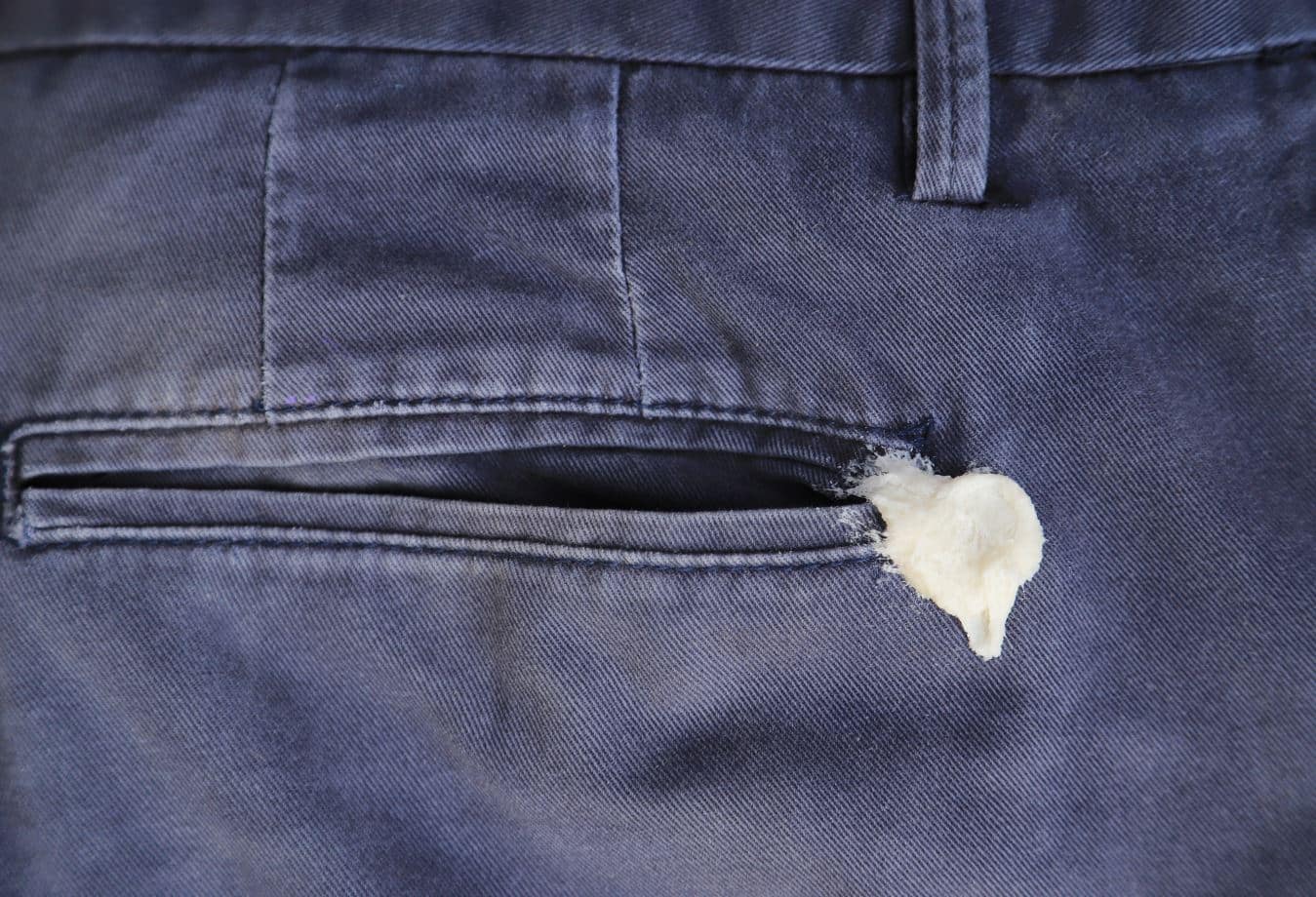 white chewing gum stuck on the back pocket of navy blue denim pants