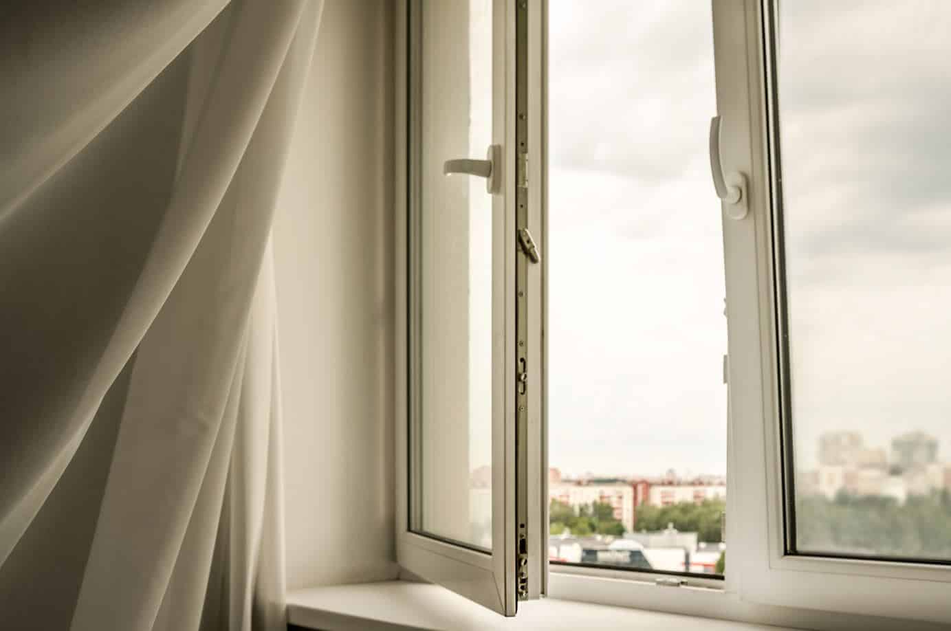 white swaying curtain due to wind next to a large open window