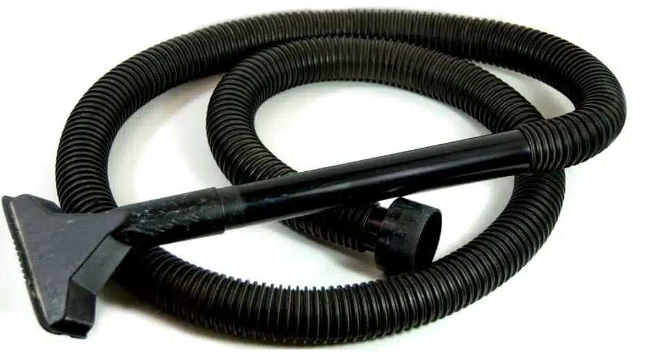 black vacuum hose curled up on the floor on a white background
