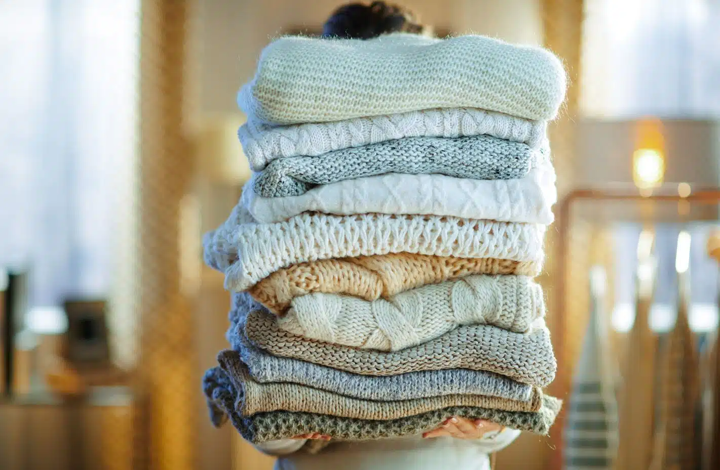 woman carrying a large heap of winter clothes