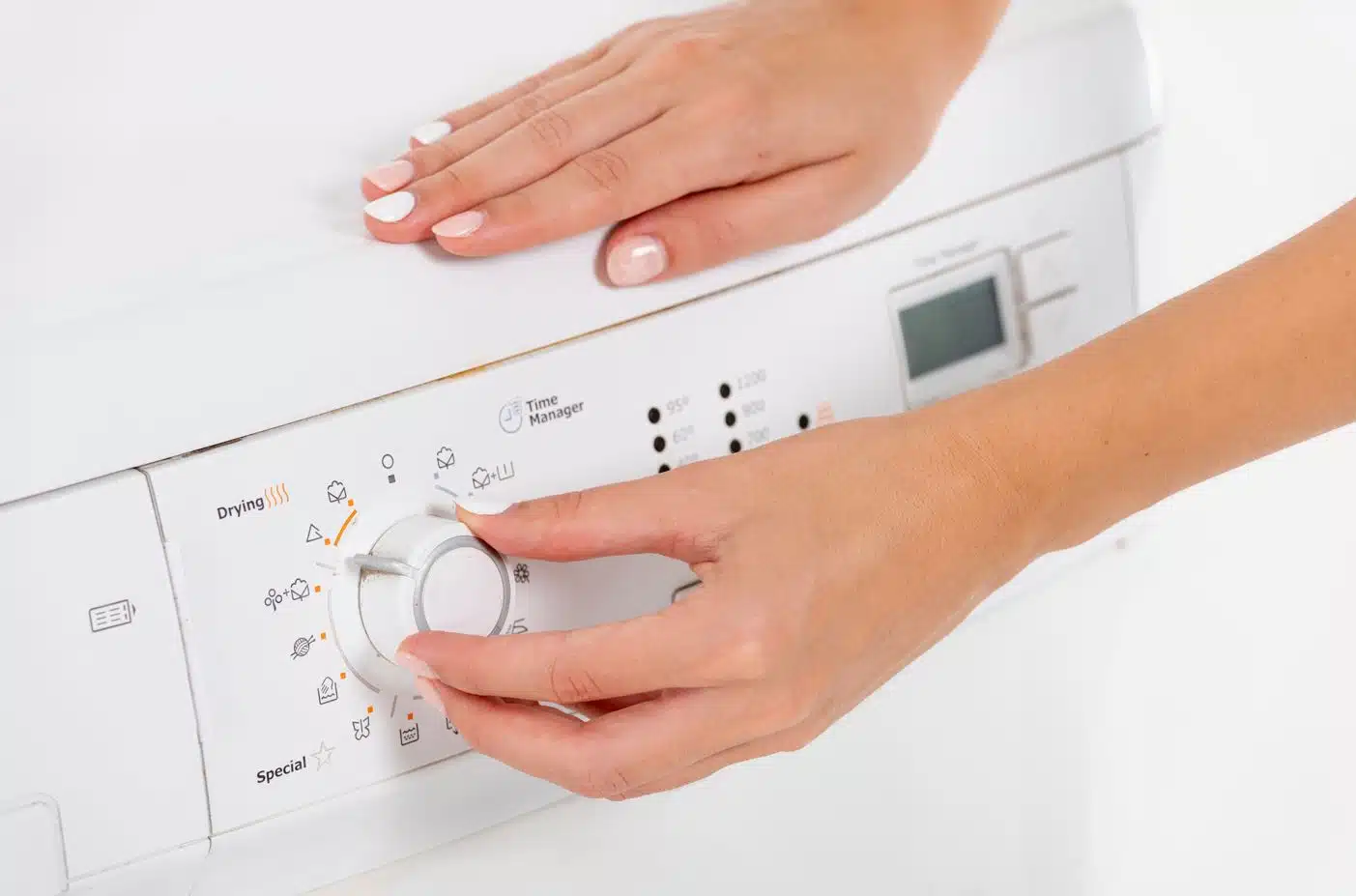 woman with white nail polish adjusting water temperature on a front load washing machine