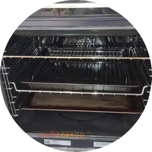 Soiled interior oven after being cleaned with a soiled oven tray on the bottom shelf