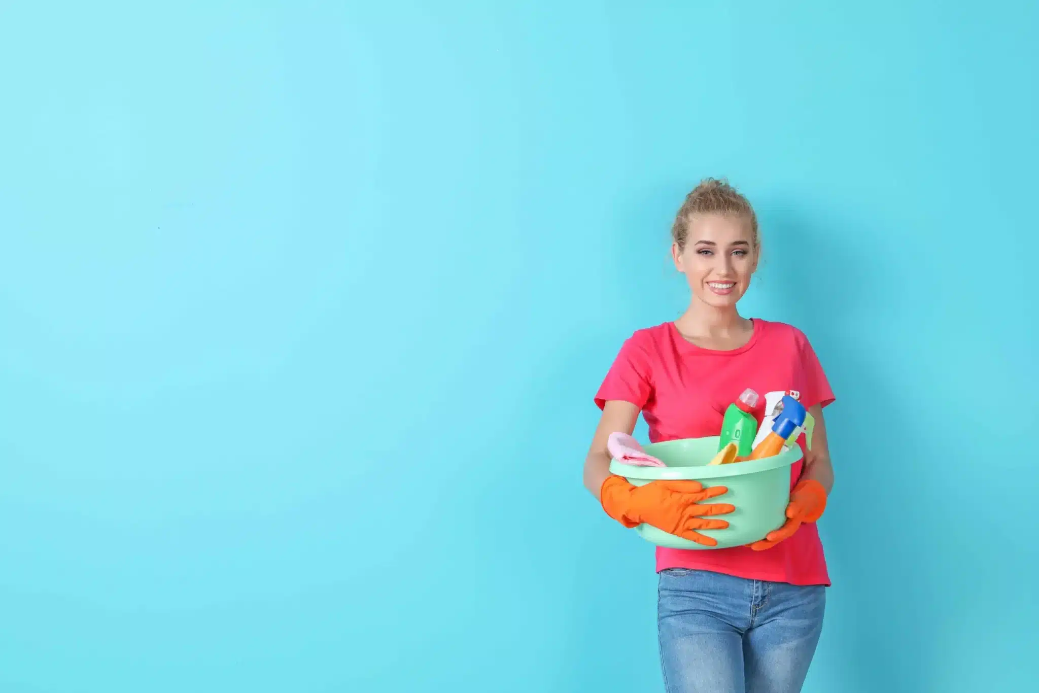 Woman holding cleaning supplies next to a blue wall